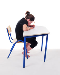 Child seated at a school desk, slumped over