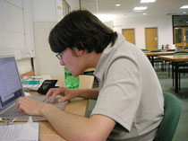 Teenager stooped over a computer